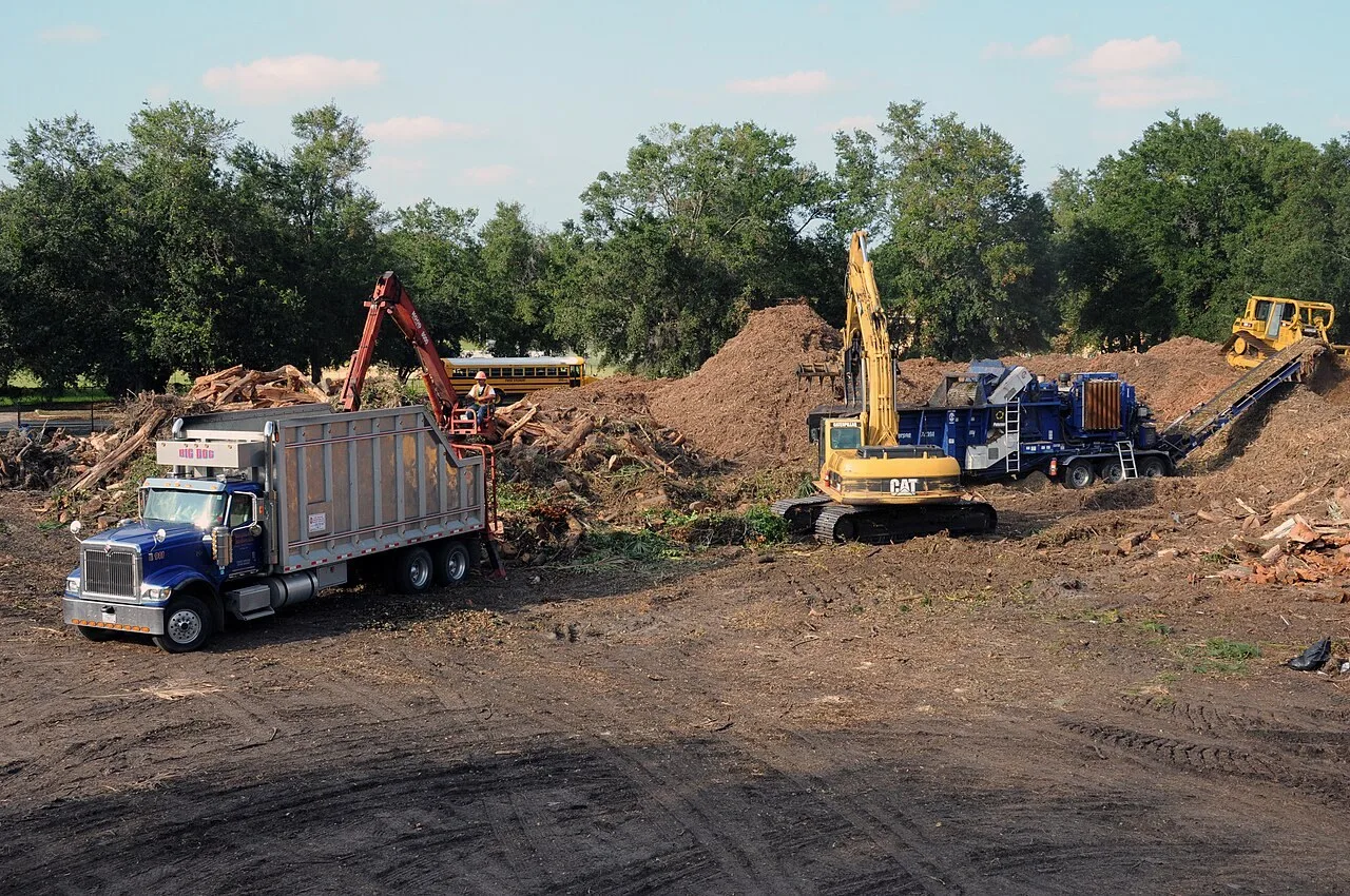 A dump truck, a Cat excavator, a wood grinder and a bulldozer working a storm debris staging site in Duval County, Jacksonville, Florida.